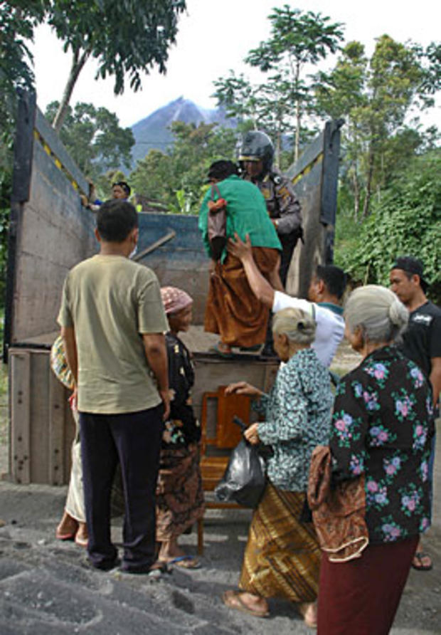 Elderly women are evacuated from a village in the Klaten district in Central Java on October 25, 2010 located in a danger zone around Mount Merapi (pictured at C in background). Indonesia ordered thousands of people to evacuate from around Mount Merapi as 