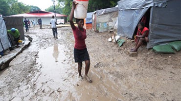 A woman carries potable water in the mud at a tent city on November 5, 2010 in Port-au-Prince. 