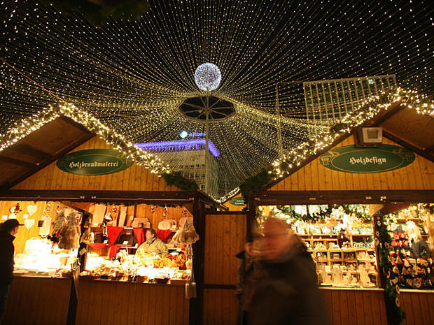 People walk through sales booths at the illuminated Christmas market in the western German city of Essen on Nov. 19, 2010. In most of the German cities, the Christmas season starts this weekend with markets, decorated streets and shopping arcades starting 