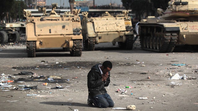 demonstrator prays near Egyptian army vehicles  