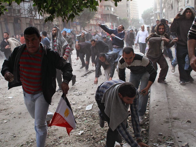 demonstrators grab for stones while charging a group of supporters 