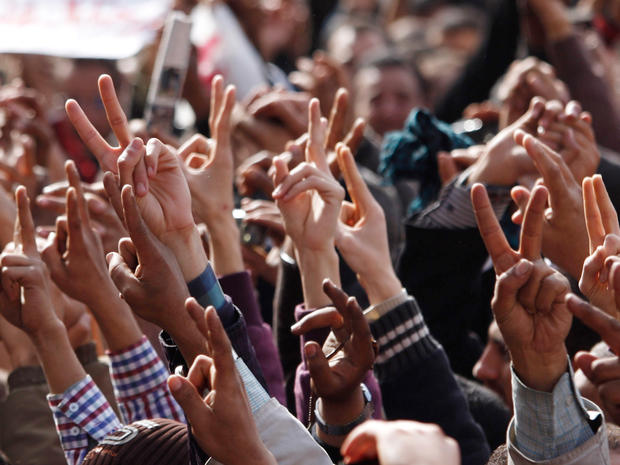protestors rise their hands in the victory sign  