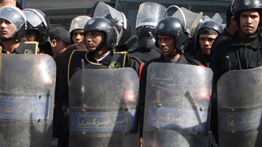 Egyptian demonstrators perform the Friday noon prayer in front of riot police during a demonstration in Cairo on January 28, 2011. 