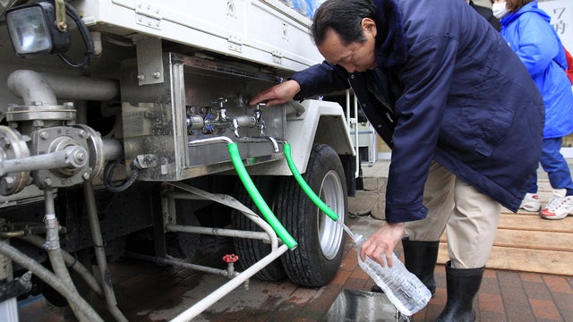 A Japanese man gets water from supply tanks near Tokyo 