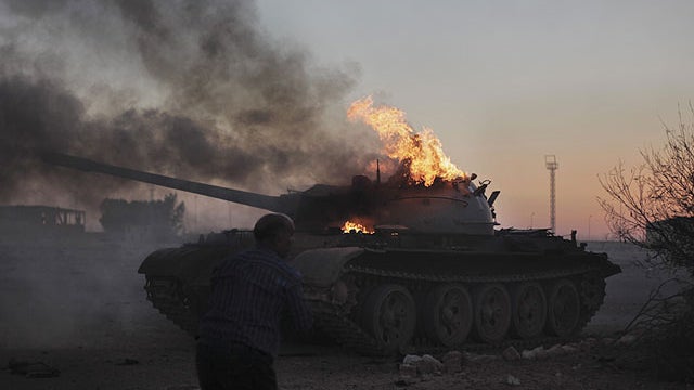 A cameraman films a pro-Qaddafi forces tank as it burns on the outskirts of Ajdabiya, in Libya, April 10, 2011.  