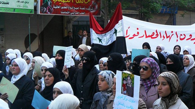 Syrian women carry a banner  