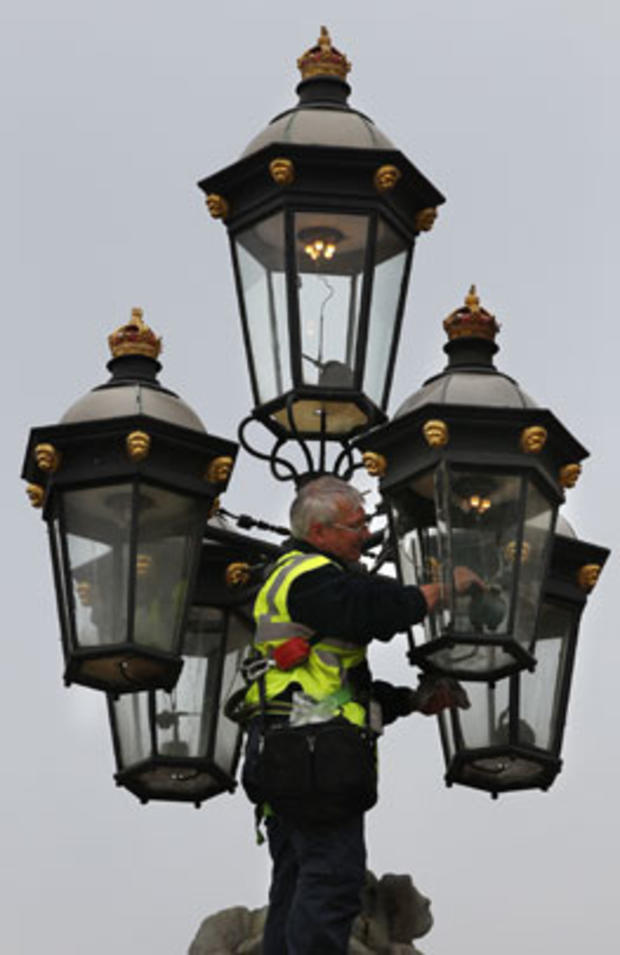 A workman makes adjustments to an ornamental gas lamp on the gates of Buckingham Palace on April 28, 2011, in London. 