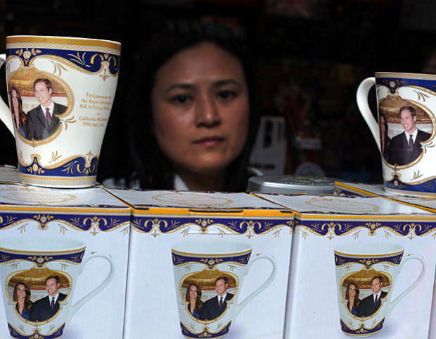 A woman looks out of a shop by a pile of commemorative mugs on sale in central London on April 28, 2011.  