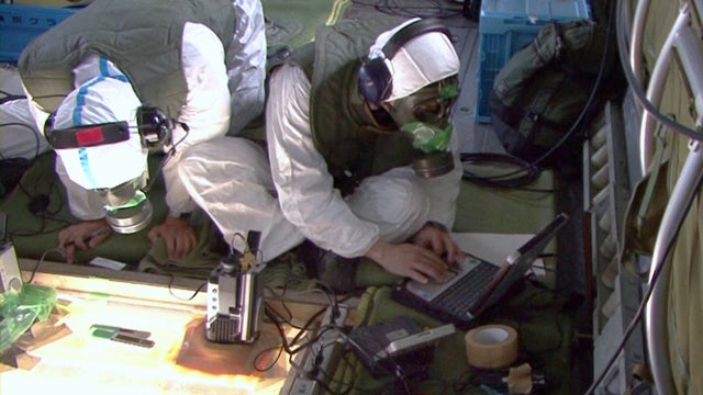 Members of the Self-Defense Forces wearing protective gear measure temperatures of the crippled Fukushima Daiichi nuclear power plant  