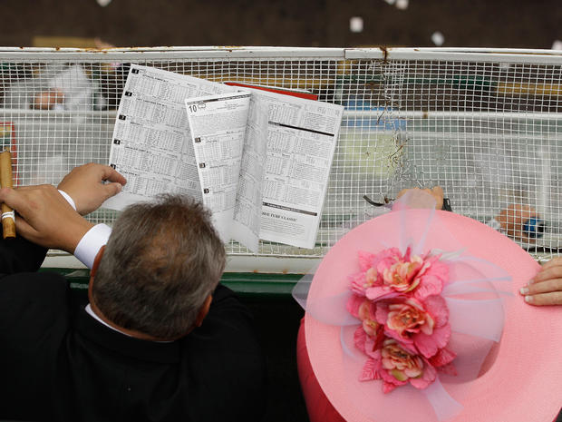 Spectators study the racing program before the 137th Kentucky Derby horse race at Churchill Downs, Saturday, May 7, 2011, in Louisville, Ky.  