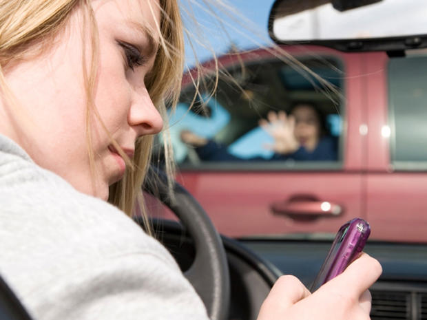 A teenager texting on her phone and looking away from the road  