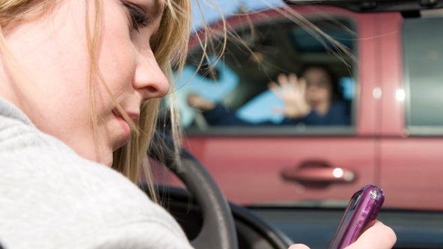 A teenager texting on her phone and looking away from the road  