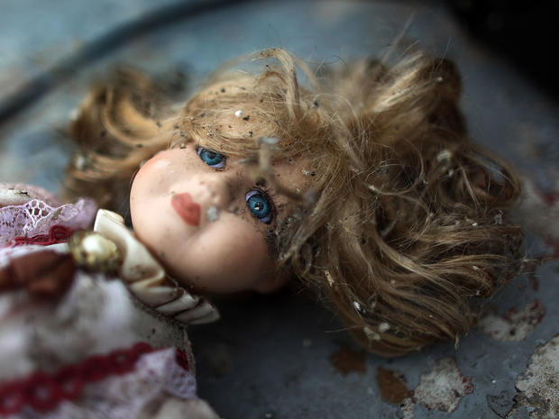 A doll lies covered in debris in a home 