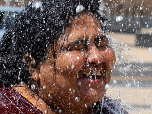 Maria Mejia cools off in a water fountain 