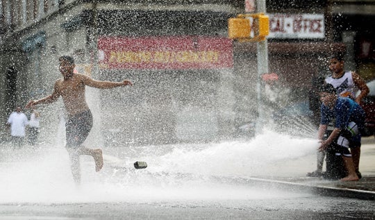 Children play in water sprayed from a fire hydrant  