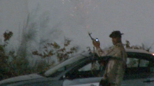 Qaddafi loyalist firing a gun in front of hotel. 