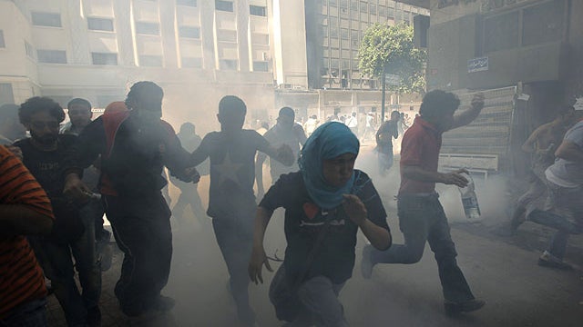 Egyptian protesters run to avoid tear gas during clashes with security forces, unseen at Tahrir Square in Cairo, Egypt, June 29, 2011.  
