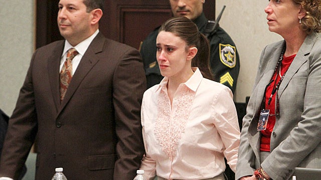 Casey Anthony holds hands with her defense attorneys, Jose Baez, left, and Dorothy Clay Sims, as they listen to the verdict 