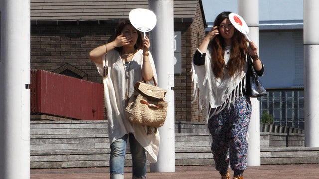 Women shield themselves from Tokyo sun with handheld fans 