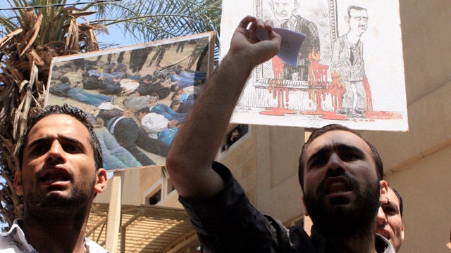 Lebanese protesters shout slogans as they carry a picture depicting the bloodied hands of Syrian President Bashar Assad and his father, former President Hafez Assad, during a rally in solidarity with Syrian anti-government protesters in Tripoli, Lebanon,  