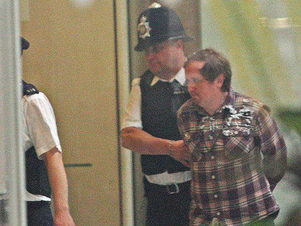 A man, named on Twitter as Jonnie Marbles, is led from Portcullis House in London, Tuesday July 19, 2011, following an incident as Rupert Murdoch and James Murdoch gave evidence before a House of Commons Committee on the News of the World phone hacking scandal. 