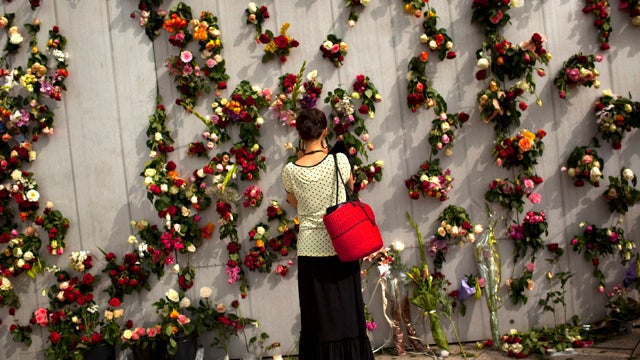 A woman is seen July 26, 2011, in front of wall decorated with flowers in memory of the victims of the July 22, 2011, bomb attack and shooting rampage in Oslo. 