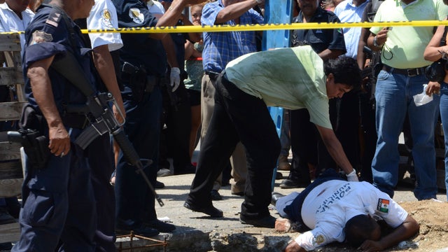 Forensic worker inspects a body after he was gunned down in Acapulco 