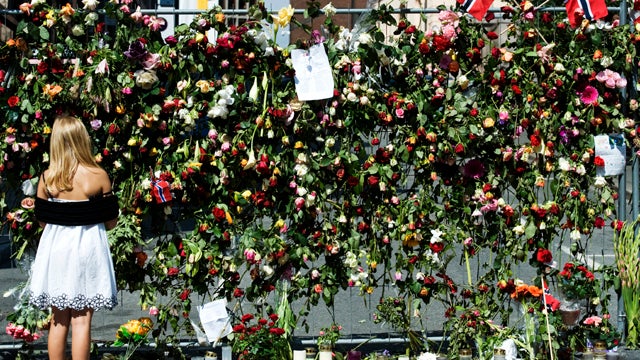 A girl looks at a security fence covered with flowers July 27, 2011, near Norway's government headquarters, which was damaged in a bomb attack July 22, 2011, in Oslo. The number of people missing after last week's mass shooting on an island near Oslo has  