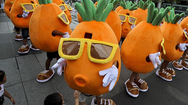 In this photo taken on Aug. 6, 2011, a total of 49 people dressed in giant carrot costumes dance on a square before Pang Kun, one of the 49 carrots, proposes to his girlfriend in Qingdao in east China's Shandong province.  