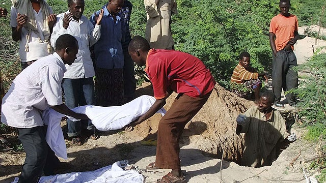 Relatives of Hassan Abdulkadir Adan,3rd left rear, from southern Somalia help to lower the body of his 7-year-old son into a grave in a refugee camp in Mogadishu, Somalia. Aug. 16, 2011. 