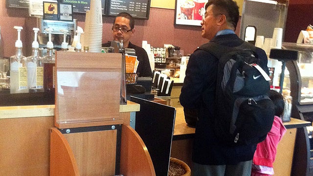 In this photo provided by ZhaoHui Tang, former Washington Gov. Gary Locke, who is the first Chinese-American ambassador to China, orders coffee at Seattle Tacoma International Airport on Aug. 12, 2011.  