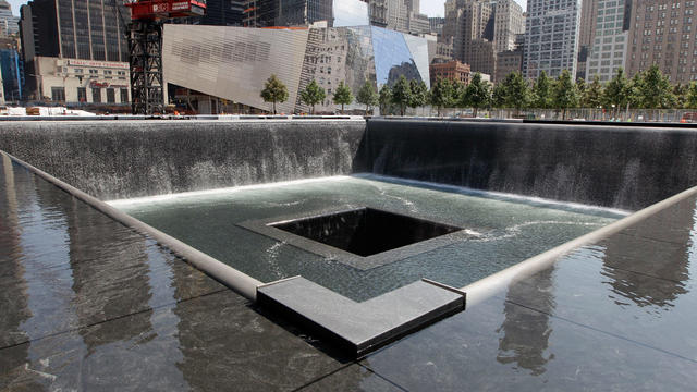 The National September 11 Memorial and Museum is seen in the background as water flows in the south pool of the World Trade Center Memorial 