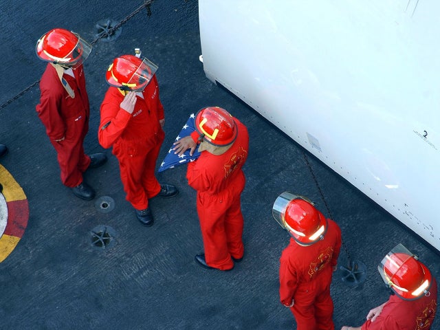 Damage controlmen and U.S. Navy firefighters pass the first American flag raised above ground zero  Sept. 30, 2001, aboard the USS Theodore Roosevelt. The flag was presented to the Theodore Roosevelt's crew to be flown during a deployment. 