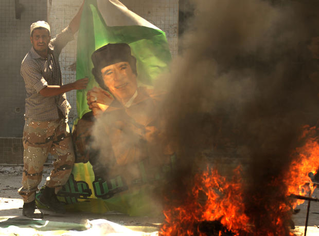 A Libyan rebel burns a poster of Moamer Kadhafi 