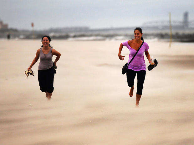 Women run along a sand-swept beach at Coney Island  