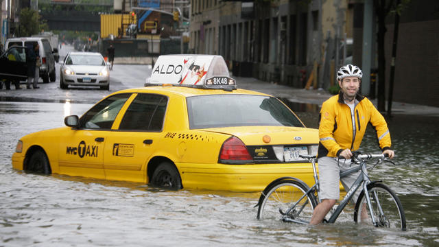 A bicyclist makes his way past a stranded taxi 