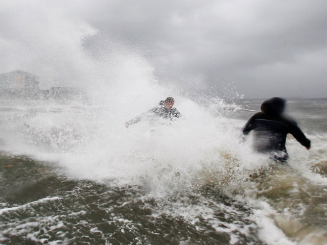 Ken Thompson, right, and Ray Morrison make their way toward their house along a seawall as winds from Tropical Storm Irene  