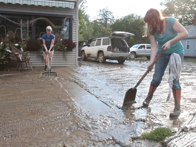 People clean mud from in front of store 