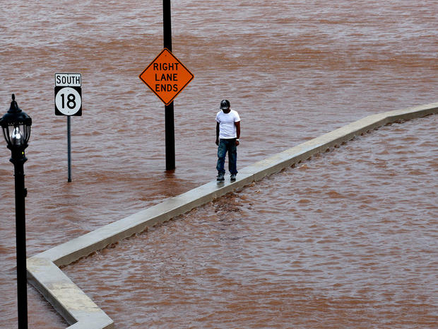A man walks on top of a wall next  to a flooded highway in New Brunswick, N.J.,  Aug. 28, 2011. 