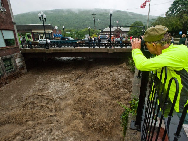 Mel Martin joins a crowd watching the raging Whetstone Brook surge over the falls in downtown Brattleboro, Vt. on  Aug. 28, 2011.  