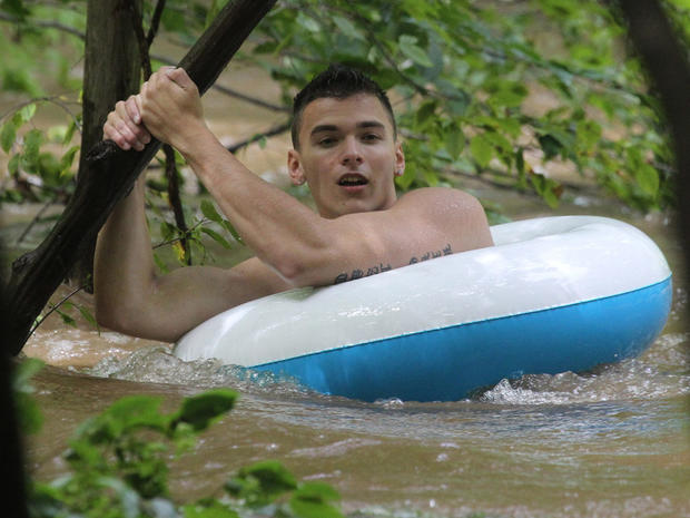 An unidentified male hangs on to a branch in a rain swollen creek as he waits for rescuers in New City, N.Y., Sunday, Aug. 28, 2011. 