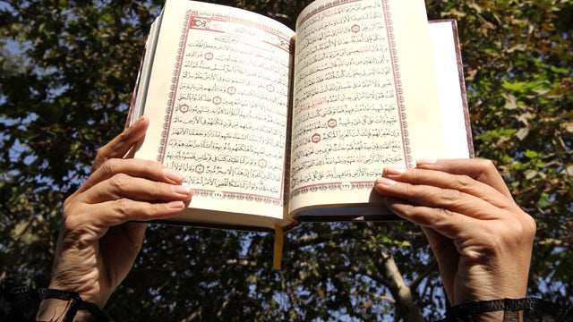 An Iranian woman holds up an open copy of the Muslim holy book, the Quran, during a protest in front of the Swiss Embassy in Tehran Sept. 13, 2010. 
