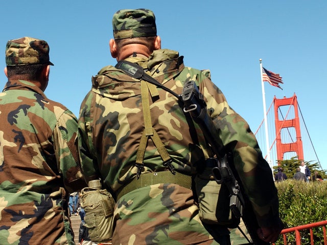 National Guardsmen look at one of the three U.S. flags recovered from ground zero during a presentation at the Golden Gate Bridge March 18, 2002, in San Francisco. New York City Police Sgt. Joe Keenan brought the flag to San Francisco as a show of appreci 