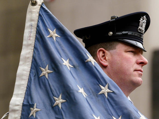 A New York City police officer stands next to a dusty U.S. flag during the re-dedication of the Millenium Hilton Hotel May 5, 2003, in New York City. The hotel, directly across from ground zero, just barely survived the downing of the World Trade Center S 