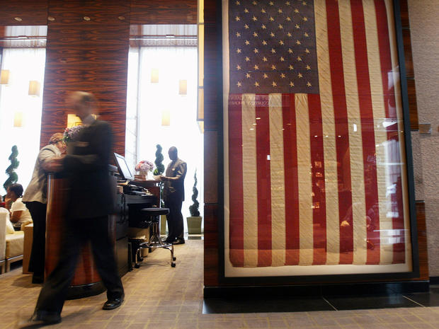 A worker walks past an American flag that flew in front of the Millenium Hilton Hotel Sept. 11, 2001, and was re-hung in the hotel's lobby Sept. 4, 2003, in New York City. The hotel is located directly across the street from ground zero. 