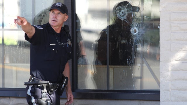With bullet holes seen in a window, officers look for evidence at the scene of a shooting at an IHOP restaurant in Carson City, Nev. on Sept. 6, 2011.  