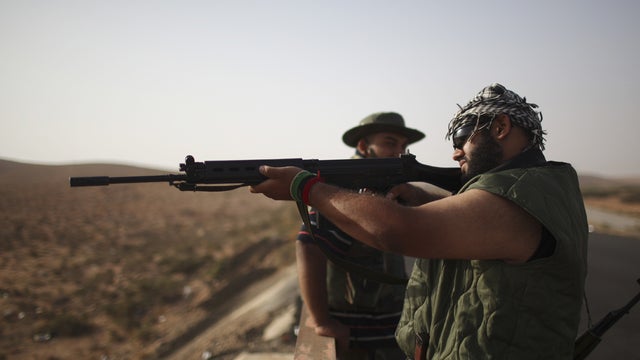 Rebels check a rifle at a checkpoint outside Bani Walid 