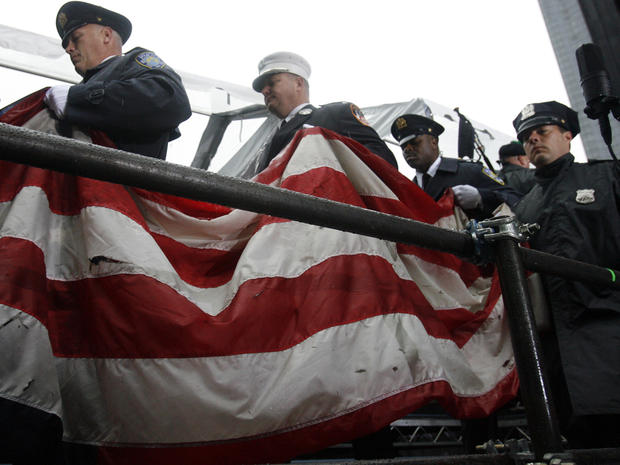 New York City firefighters carry an American flag which survived the 9/11 attacks as people gather at ground zero during a memorial ceremony Sept. 11, 2009, in New York. 