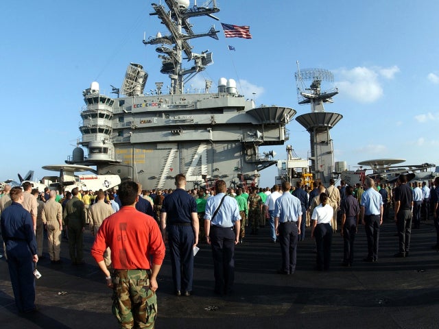 U.S. sailors and Marines come to attention during the national anthem as an American flag, which was found in the rubble of the World Trade Center, is raised Dec. 17, 2001, in support of Operation Enduring Freedom aboard the USS John C. Stennis. The flag  