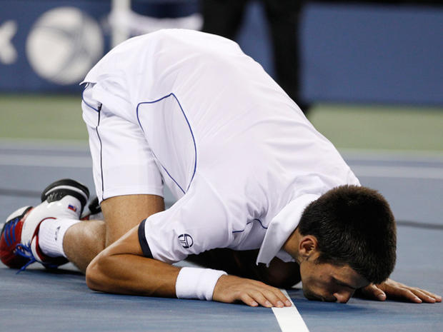 Novak Djokovic kisses the court after winning the men's championship match 